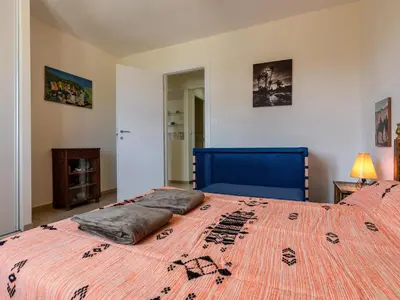 a bedroom with a large bed with a blue head board at Holiday Home Agula Marina by Interhome in Moriani Plage