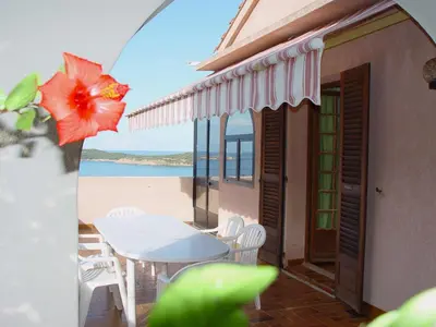 a table and chairs on a balcony with a view of the ocean at Residence ELLADA 1 in Cargèse