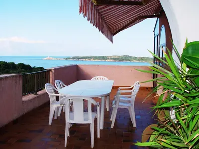 a white table and chairs on a balcony with the ocean at Residence ELLADA 1 in Cargèse