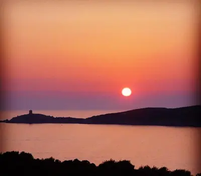 a sunset over a body of water with a lighthouse at Residence ELLADA 1 in Cargèse