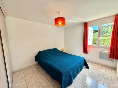 a bedroom with a blue bed and a window at Appartement avec piscine privée Porticcio in Porticcio