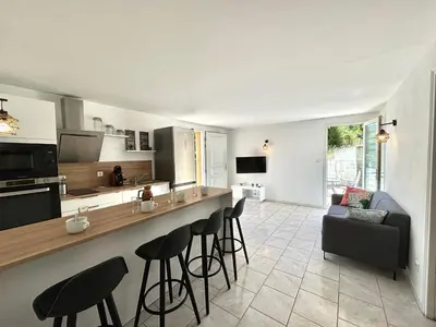 a kitchen and living room with a counter and stools at Appartement avec piscine privée Porticcio in Porticcio