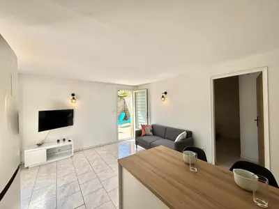 a living room with a couch and a television at Appartement avec piscine privée Porticcio in Porticcio