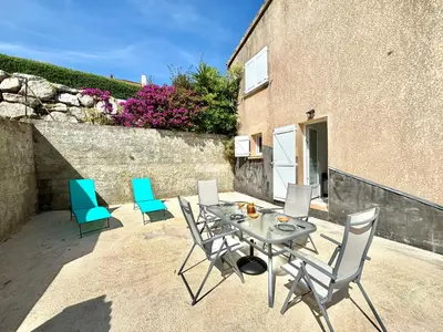 a patio with a table and chairs and a building at Appartement avec piscine privée Porticcio in Porticcio