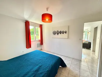 a bedroom with a blue bed and a window at Appartement avec piscine privée Porticcio in Porticcio
