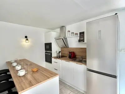 a kitchen with white cabinets and a wooden counter top at Appartement avec piscine privée Porticcio in Porticcio