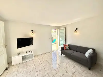 a living room with a couch and a flat screen tv at Appartement avec piscine privée Porticcio in Porticcio