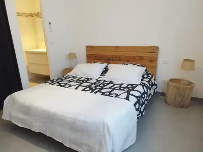 a bedroom with a large bed with a wooden headboard at Villa Katiris in Porto-Vecchio