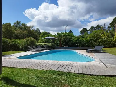 a swimming pool with chairs and an umbrella at Villa Katiris in Porto-Vecchio