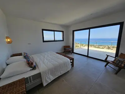 a bedroom with a bed and a view of the ocean at LABELLE- Vue mer panoramique - Piscine privée - Clim -WIFI in Sari Solenzara