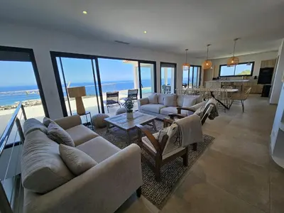 a living room with couches and a living room with the ocean at LABELLE- Vue mer panoramique - Piscine privée - Clim -WIFI in Sari Solenzara