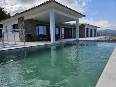 a villa with a swimming pool in front of a house at LABELLE- Vue mer panoramique - Piscine privée - Clim -WIFI in Sari Solenzara