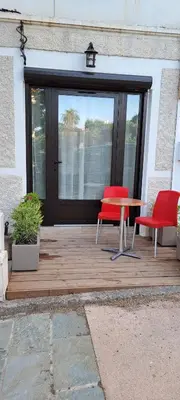 a wooden deck with two red chairs and a table at Charmant studio neuf Ajaccio Casone - Trottel in Ajaccio