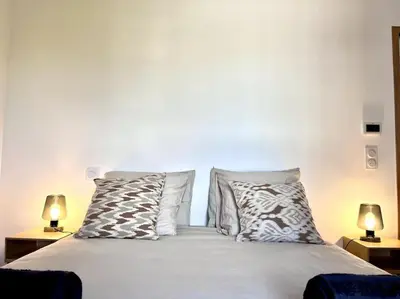 a bedroom with a bed with pillows and two lamps at Appartement neuf centre-ville in Porto-Vecchio
