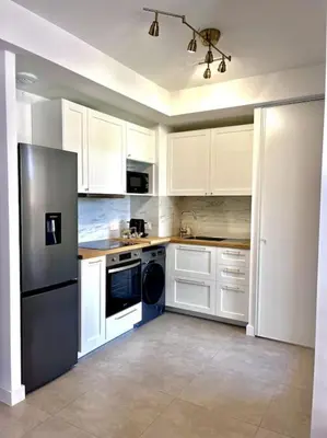 a kitchen with white cabinets and a black refrigerator at Appartement neuf centre-ville in Porto-Vecchio