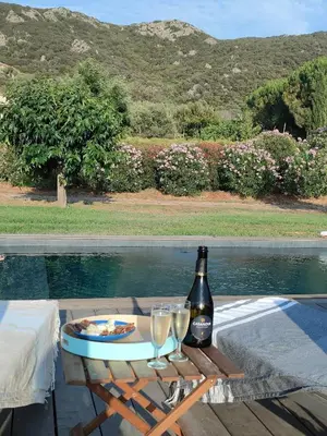 a table with a bottle of wine and two glasses at Villa Callochiusa avec piscine 15mn Bonifacio in Figari