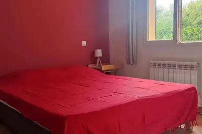 a red bed in a bedroom with a red blanket at Villa Callochiusa avec piscine 15mn Bonifacio in Figari
