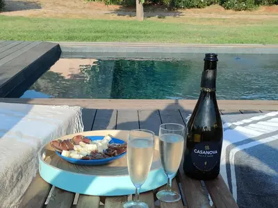 a bottle of wine and glasses on a table with a plate of food at Villa Callochiusa avec piscine 15mn Bonifacio in Figari