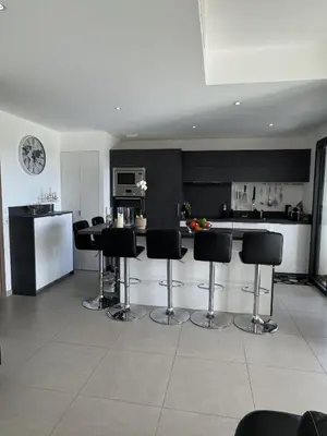 a kitchen with black and white counters and bar stools at Appartement dernier étage avec spa privatif sur grande terrasse in Porto-Vecchio