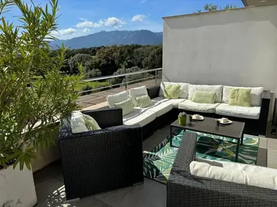 a patio with a couch and chairs and a table at Appartement dernier étage avec spa privatif sur grande terrasse in Porto-Vecchio