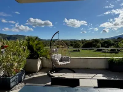 a chair on a patio with a view of a field at Appartement dernier étage avec spa privatif sur grande terrasse in Porto-Vecchio
