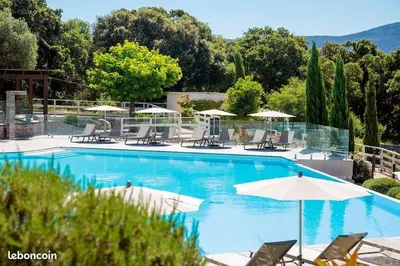a large swimming pool with chairs and umbrellas at Appartement dernier étage avec spa privatif sur grande terrasse in Porto-Vecchio