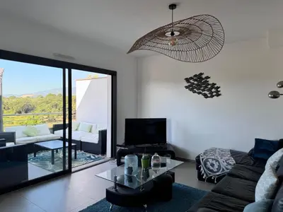 a living room with a couch and a glass table at Appartement dernier étage avec spa privatif sur grande terrasse in Porto-Vecchio