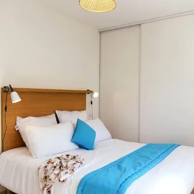 a white bed with a blue blanket on top of it at Appt T4 Accès Plage, piscine privée, clim N3-4 in Linguizzetta