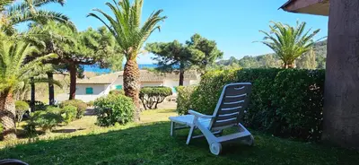 a blue rocking chair sitting in a yard with palm trees at ORO 3-Piscine en résidence- Tennis-Wifi in Conca