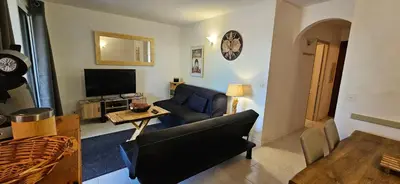 a living room with a couch and a tv at ORO 3-Piscine en résidence- Tennis-Wifi in Conca