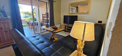a living room with a couch and a television at ORO 3-Piscine en résidence- Tennis-Wifi in Conca