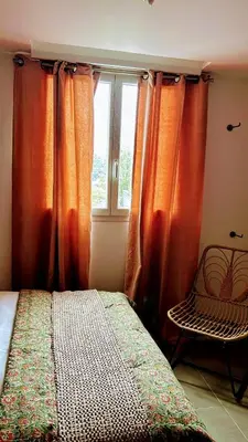 a bedroom with orange curtains and a bed and a window at Casa Carlu Maria III in Corte