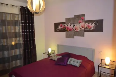 a bedroom with a red bed with two lamps and flowers on the wall at Villa Mare e Machja in Zonza