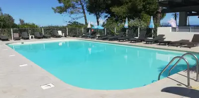 a large blue swimming pool with chairs around it at Les pieds dans l'eau in San-Nicolao