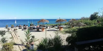 a beach with chairs and umbrellas and the ocean at Les pieds dans l'eau in San-Nicolao