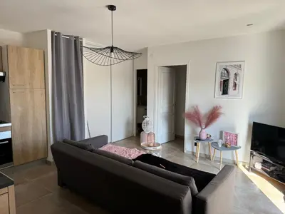 a living room with a black couch and a tv at Logement 5 mn de la mer Milla 2 in Ventiseri