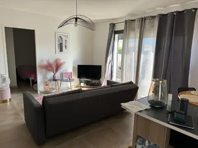 a living room with a black couch and a tv at Logement 5 mn de la mer Milla 2 in Ventiseri