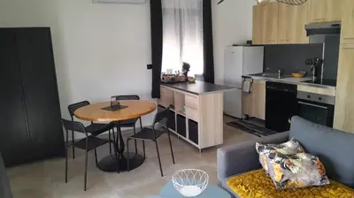 a living room with a table and a kitchen at Logement 5 mn de la mer Milla 2 in Ventiseri