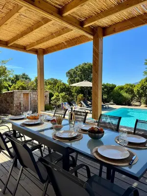 a table and chairs on a patio with a swimming pool at Villa avec Piscine proche plages et commerces in San-Gavino-di-Carbini
