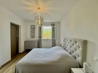 a bedroom with a large bed and a chandelier at Villa avec Piscine proche plages et commerces in San-Gavino-di-Carbini