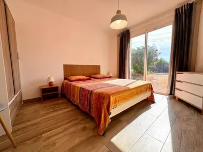 a bedroom with a bed and a large window at Villa avec Piscine proche plages et commerces in San-Gavino-di-Carbini