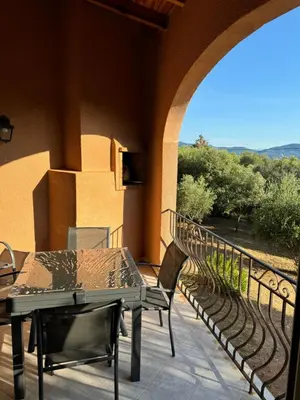 a patio with a table and chairs on a balcony at villa arbutu in Olmeto