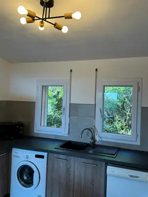 a kitchen with a washing machine and two windows at villa arbutu in Olmeto