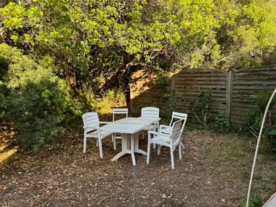 a white table and chairs sitting in a yard at villa arbutu in Olmeto