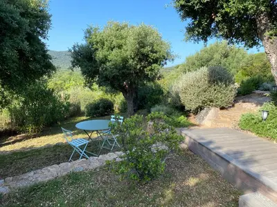 a table and chairs in a garden with a tree at Les Bergeries de Pinarello, Capellina in Zonza