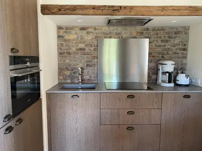 a kitchen with wooden cabinets and a metal appliance at Les Bergeries de Pinarello, Capellina in Zonza