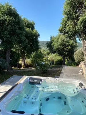 a jacuzzi tub in a yard with trees at Les Bergeries de Pinarello, Capellina in Zonza