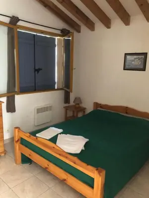 a bedroom with a green bed and a window at Villa acula in Olmeto