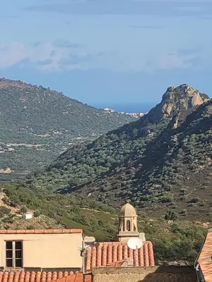 a view of a building with a mountain in the background at La maison de corse in Feliceto