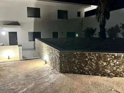 a stone retaining wall in front of a house at night at Résidence du Château d'eau in Porticcio